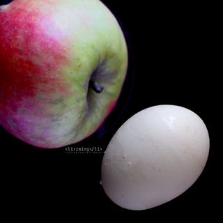 An apple and an egg on black background.