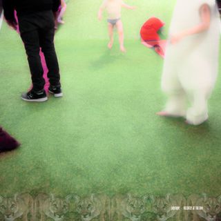 Artificial grass, black dressed person standing on left, a half-dressed kid centered in background, a fluffy white dressed person on right. All heads are cropped out of the frame.