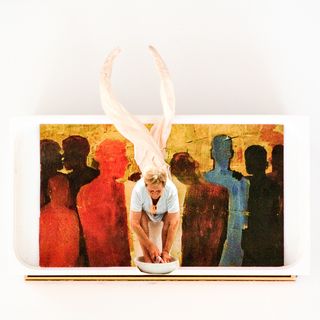 Collage in a wide box. Center: White-dressed sitting woman, washing her feet in a white bowl. Out of her head intertwined paper twists are growing, like two giant horns. Warmly water-colored (uni) people shades behind her, standing.